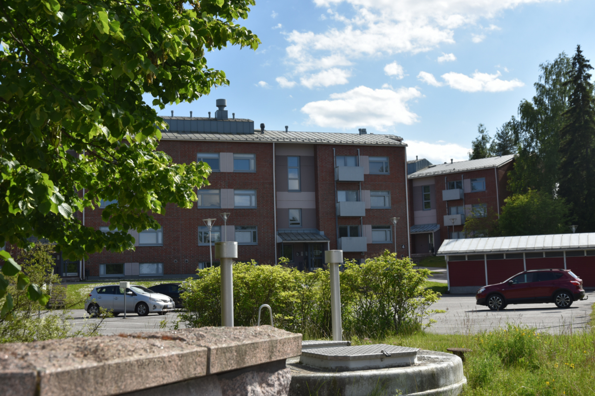 Kerrostaloja, parkkipaikkoja ja luontoa.